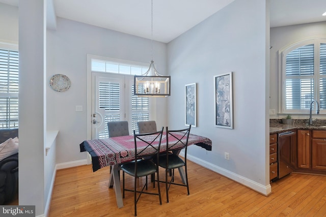 dining space with sink, an inviting chandelier, and light hardwood / wood-style floors