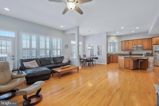 living room with a healthy amount of sunlight, ceiling fan with notable chandelier, and light wood-type flooring