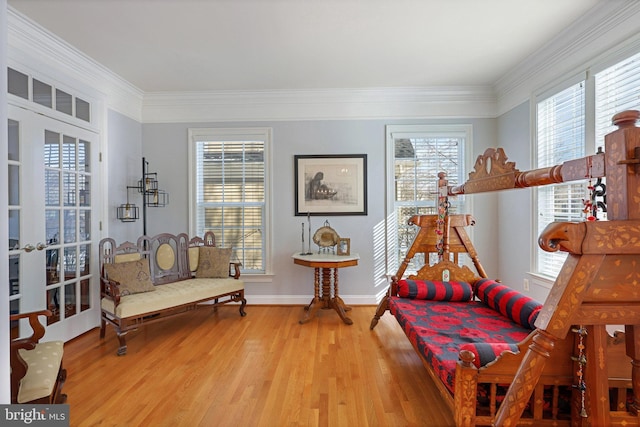 living area with hardwood / wood-style flooring, ornamental molding, and french doors