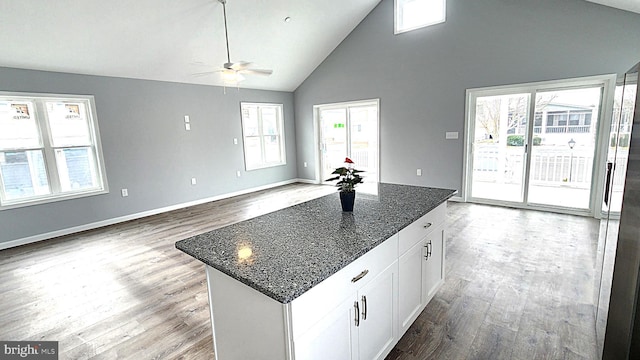 kitchen featuring white cabinetry, a center island, a healthy amount of sunlight, and dark stone counters