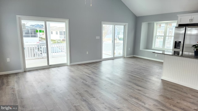 unfurnished living room featuring wood-type flooring, high vaulted ceiling, and a healthy amount of sunlight