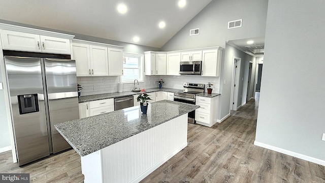 kitchen featuring white cabinetry, appliances with stainless steel finishes, a center island, and decorative backsplash