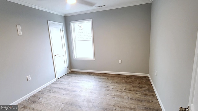 empty room with crown molding and light hardwood / wood-style floors