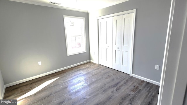 unfurnished bedroom with hardwood / wood-style flooring, ornamental molding, and a closet