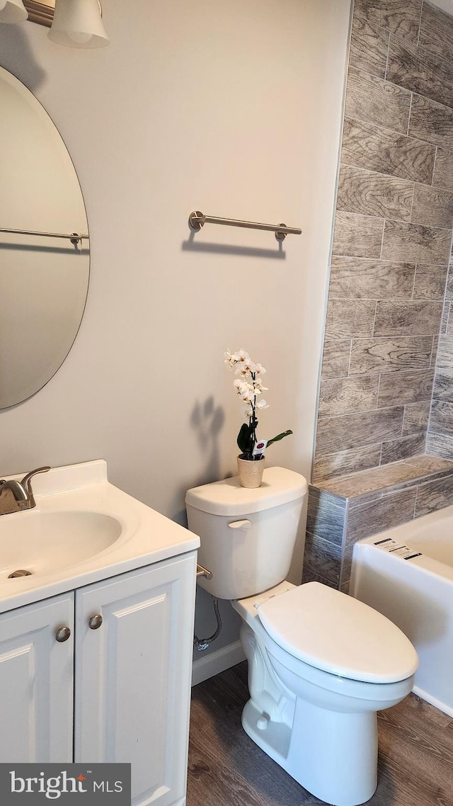 bathroom featuring vanity, hardwood / wood-style floors, a bath, and toilet