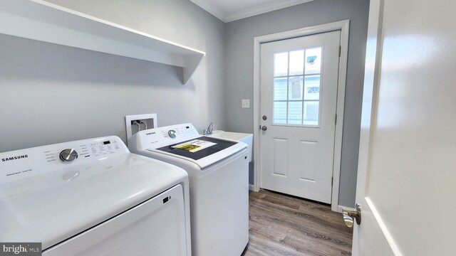 laundry room with crown molding, washing machine and clothes dryer, and light hardwood / wood-style floors