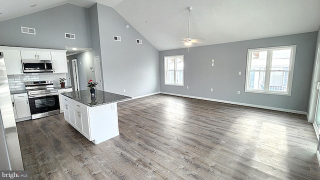 kitchen with white cabinetry, appliances with stainless steel finishes, decorative backsplash, and dark stone counters