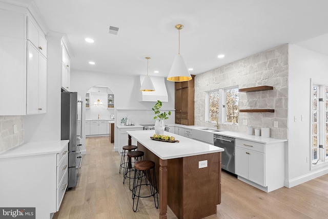 kitchen featuring a center island, hanging light fixtures, appliances with stainless steel finishes, decorative backsplash, and white cabinets