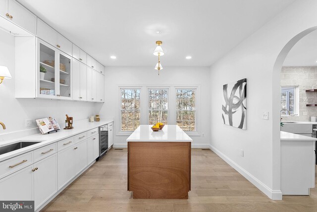 kitchen featuring wine cooler, sink, white cabinets, and a kitchen island