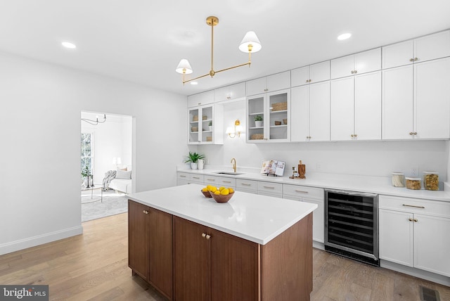 kitchen featuring wine cooler, white cabinetry, light wood-type flooring, and a kitchen island