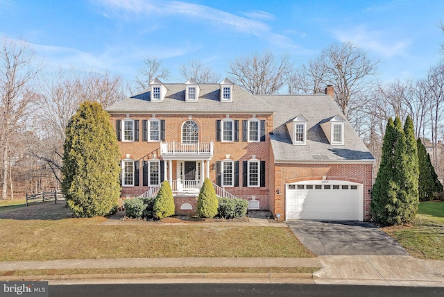 colonial-style house featuring a garage, a front lawn, and a porch