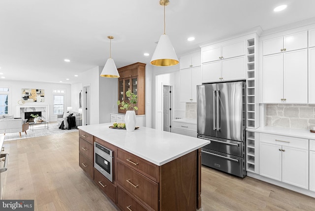 kitchen featuring stainless steel appliances, light hardwood / wood-style flooring, hanging light fixtures, and white cabinets