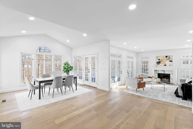 dining area with a fireplace, light hardwood / wood-style flooring, french doors, and plenty of natural light