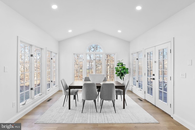 dining room with lofted ceiling, french doors, and light wood-type flooring