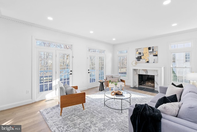 living room featuring ornamental molding, a high end fireplace, and light hardwood / wood-style floors