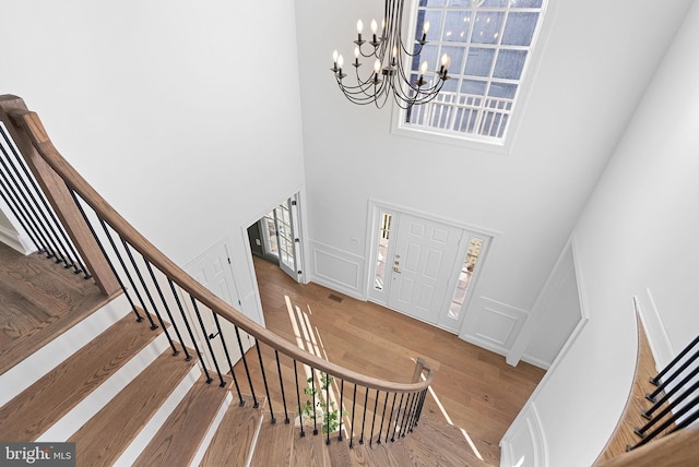 foyer entrance with an inviting chandelier, hardwood / wood-style floors, and a high ceiling