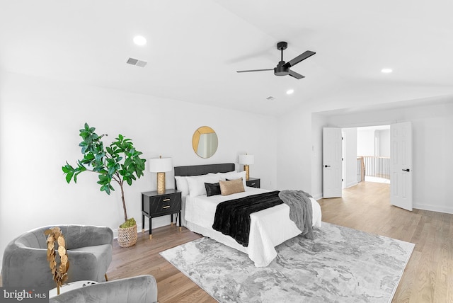 bedroom with ceiling fan, light hardwood / wood-style floors, and vaulted ceiling