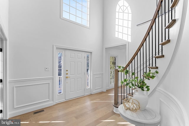 foyer featuring a towering ceiling and light hardwood / wood-style floors