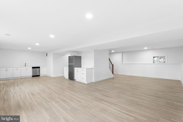 basement featuring fridge, light hardwood / wood-style floors, and indoor bar