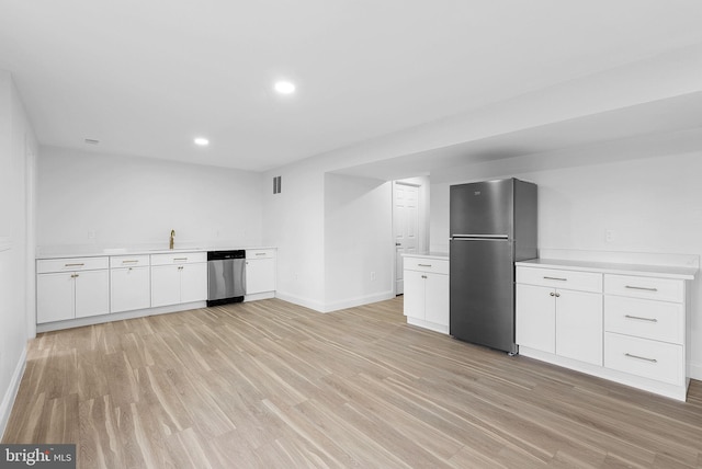 kitchen with stainless steel appliances, sink, light hardwood / wood-style floors, and white cabinets