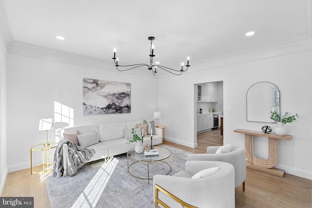 living room with ornamental molding, a chandelier, and light wood-type flooring