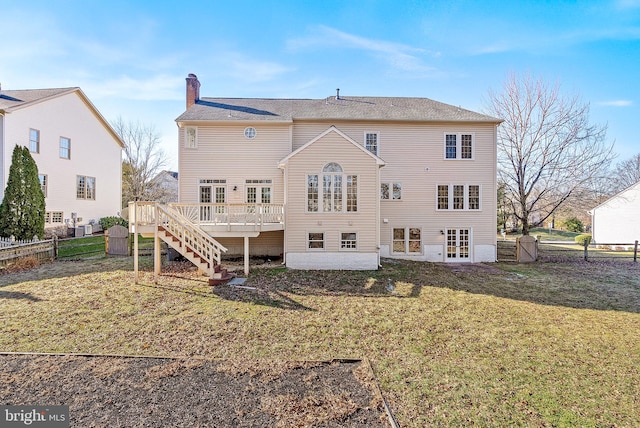 rear view of property featuring a wooden deck and a lawn