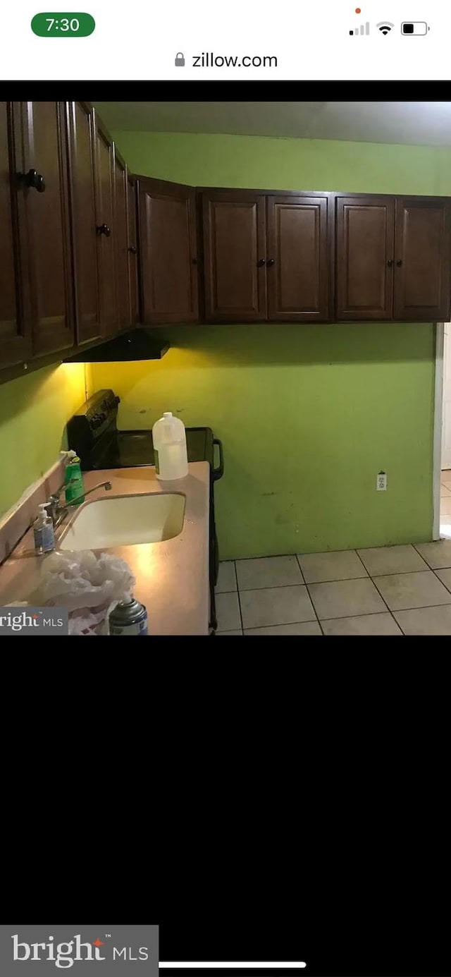 kitchen featuring sink, dark brown cabinetry, and light tile patterned flooring