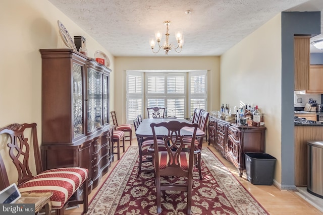 dining room featuring light hardwood / wood-style floors, a textured ceiling, and a notable chandelier