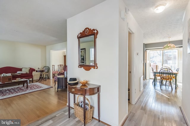 hallway featuring light hardwood / wood-style floors and a textured ceiling