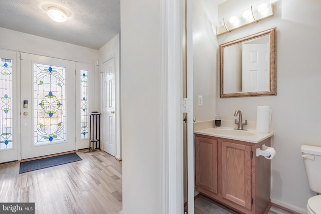 foyer entrance featuring sink, a textured ceiling, and light hardwood / wood-style flooring