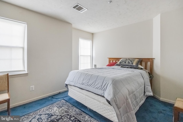 bedroom featuring a textured ceiling, multiple windows, and carpet floors