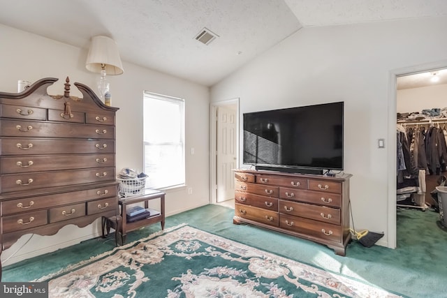 bedroom featuring a textured ceiling, a walk in closet, a closet, carpet, and lofted ceiling