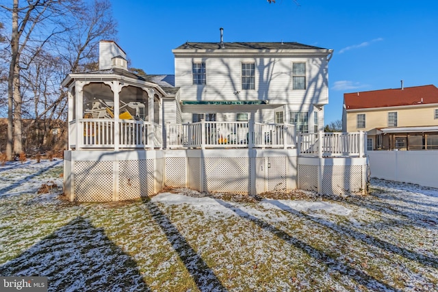 snow covered house featuring a deck and a sunroom