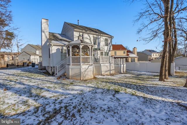 snow covered house featuring a gazebo and a wooden deck