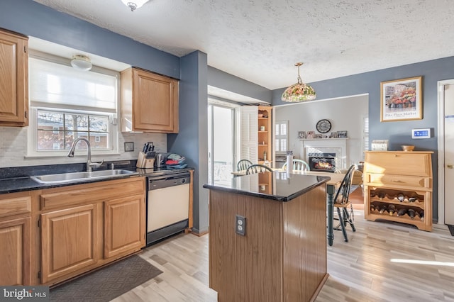 kitchen featuring a center island, dishwashing machine, a textured ceiling, and sink