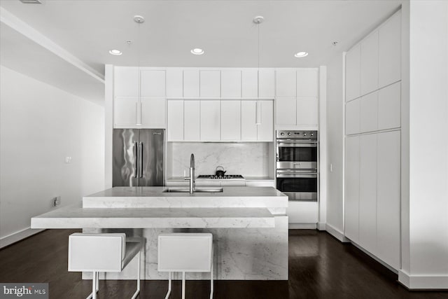 kitchen with a center island with sink, white cabinetry, and stainless steel appliances