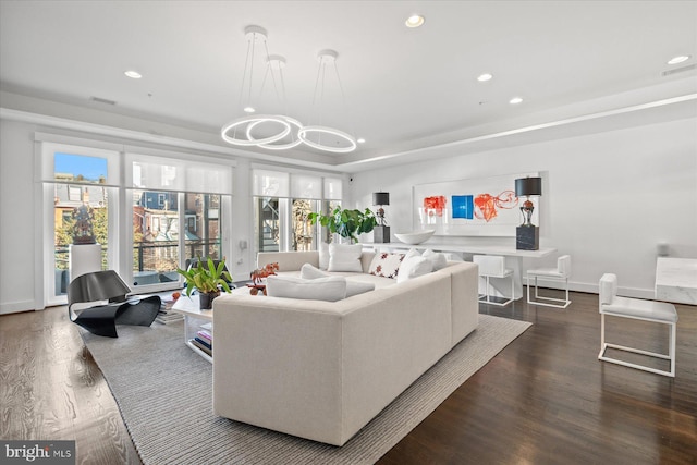 living room with a raised ceiling and dark hardwood / wood-style floors