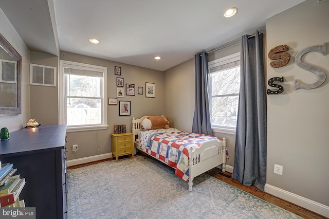 bedroom with multiple windows and hardwood / wood-style flooring