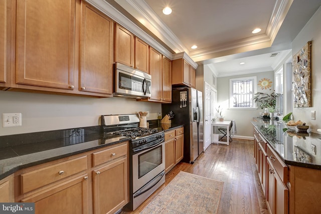 kitchen with light hardwood / wood-style floors, dark stone countertops, crown molding, and appliances with stainless steel finishes