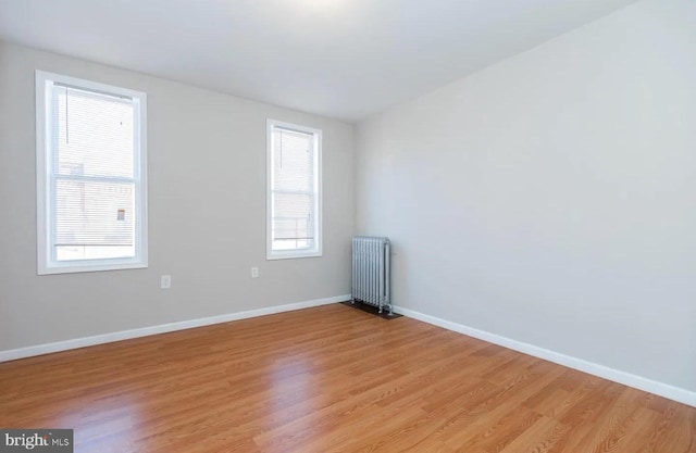 spare room featuring radiator heating unit and light wood-type flooring