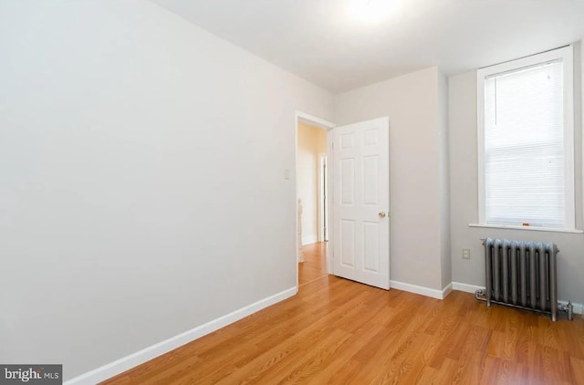 spare room featuring radiator heating unit and light hardwood / wood-style floors