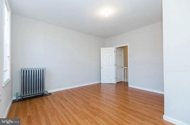 empty room with radiator heating unit and light hardwood / wood-style floors