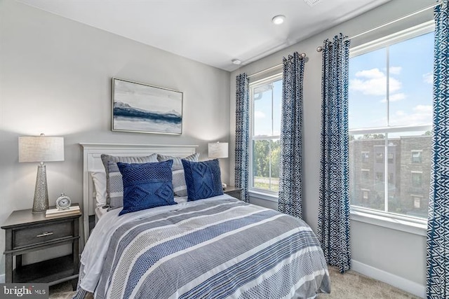 bedroom featuring light carpet and multiple windows