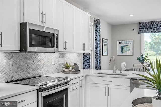 kitchen with sink, white cabinetry, stainless steel appliances, and tasteful backsplash