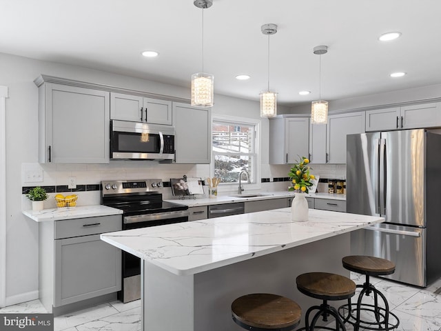 kitchen featuring sink, pendant lighting, appliances with stainless steel finishes, and a kitchen island