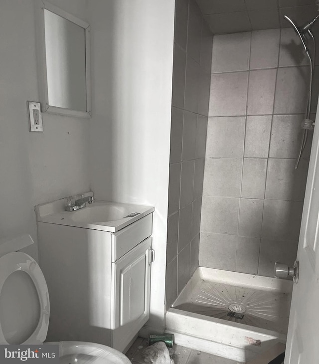 bathroom featuring vanity, toilet, and a tile shower