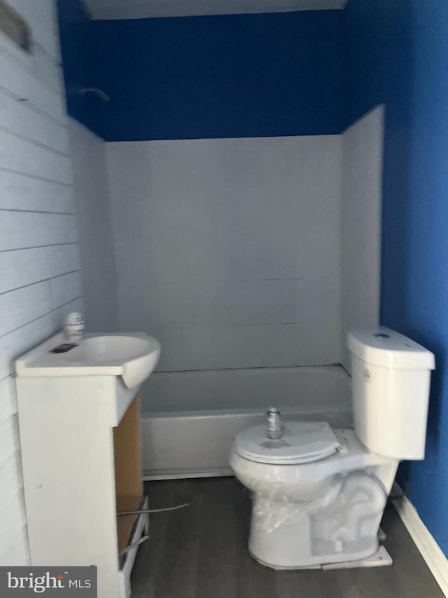 bathroom with wooden walls, toilet, and vanity