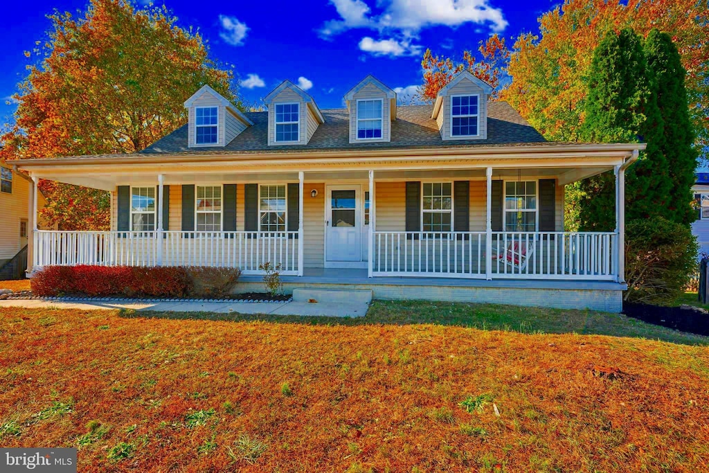 cape cod-style house featuring a front yard and a porch