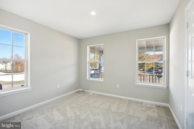 unfurnished room with light colored carpet and plenty of natural light