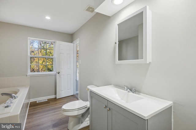 bathroom featuring vanity, toilet, hardwood / wood-style floors, and a washtub